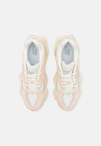 Valge ja helesoorik New Balance 9060 jooksujalatseid vaadatakse pealt, valgel taustal.