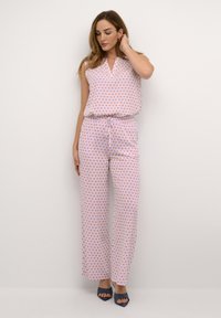 Jumpsuit bez rukava s V-izrezom, s bijelom podlogom i narančastim i plavim dijamantnim uzorcima, elastičnom strukom i širokim hlačama.