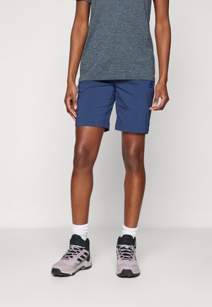 Blue athletic shorts with a short inseam and folded hem, paired with gray moisture-wicking t-shirt and light purple hiking shoes.
