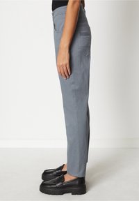 Pantalones grises de pierna recta con una cintura de altura media, hechos de una mezcla de algodón; cuentan con un bolsillo trasero y detalles en la costura lateral.