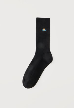 Schwarze Crew-Socke mit kleinem buntem Orb-Logo, das nahe dem oberen Rand auf einem schlichten hellen Hintergrund gestickt ist.