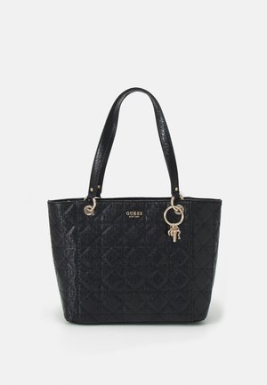 Black quilted tote bag with double handles, gold logo plaque, and gold key and lock charms on the front right side.