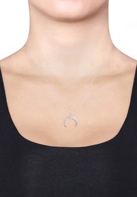 Collana d'argento con un pendente a forma di mezzaluna, caratterizzata da una delicata catena e una texture liscia, indossata su una maglietta nera su uno sfondo neutro.