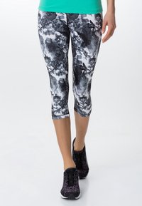 Leggings a 3/4 con un motivo floreale in bianco e nero, realizzati in tessuto elastico. Orli rifiniti, abbinati a scarpe da ginnastica nere.