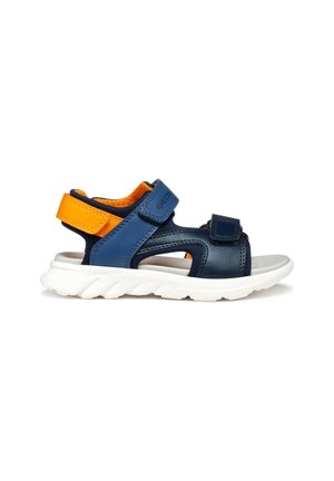 Mørkeblå lædersandal med orange detaljer, med en formet hvid sål og justerbare Velcro-stropper for sikker pasform.
