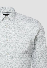 Weißes Hemd zum Knöpfen mit hellgrauem Blattmuster und umgelegtem Kragen, gezeigt von der Brust bis zur Schulter vor neutralem Hintergrund.