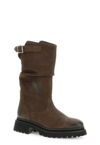 Bota de cuero marrón hasta la rodilla con un cuffs ligeramente enrollado, tira ajustable con hebilla y suela de goma negra resistente. Textura suave con un diseño minimalista.
