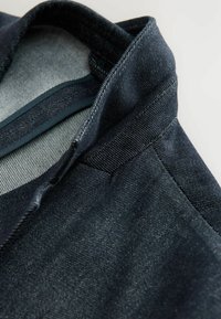 Dunkelblaue Jeansjacke mit einem strukturierten Kragen und subtiler Textur. Verfügt über ein hellgraues Futter und detaillierte Nähte entlang der Nähte.