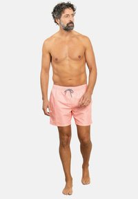 Bañador corto en rosa claro con un patrón geométrico texturizado, cinturilla elástica y detalle de cordón; tejido ligero adecuado para actividades en el agua.