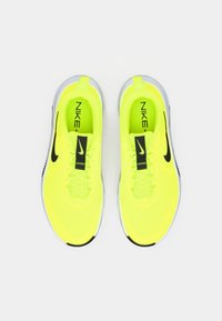 Νεον κίτρινες αθλητικές παπούτσια Nike με μαύρες λεπτομέρειες, featuring πλέγμα άνω μέρος, υφασμάτινα κορδόνια και αφρώδη σόλα. Λογότυπο στη γλώσσα.