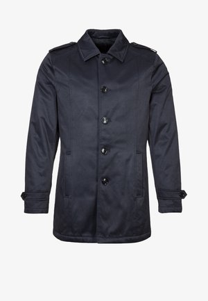 Laivastonsininen takki, joka on valmistettu sileästä kankaasta. Siinä on etuosassa nappikiinnitys, olkatoppaukset ja sivutaskut. Suora leikkaus ja pitkät hihat.