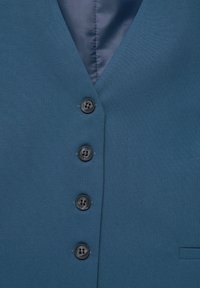 Gilet bleu sur mesure avec quatre boutons noirs et un décolleté en V, laissant apparaître partiellement une doublure intérieure sombre en haut.