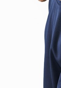 Camisa de tela azul marino con corte holgado, escote redondeado y mangas cortas. Textura suave sin patrones visibles ni detalles de metal.