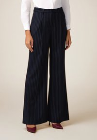 Marineblauwe wijde broek met verticale witte strepen, uitgerust met een getailleerde taille en riemlussen, gemaakt van een soepele stof.