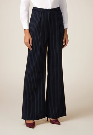 Marineblauwe wijde broek met verticale witte strepen, uitgerust met een getailleerde taille en riemlussen, gemaakt van een soepele stof.