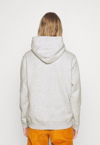 Grijze hoodie van zachte stof, met een grote capuchon, geribbelde manchetten en een gebande zoom, gedragen met oranje corduroy broek.