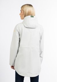 Chaqueta impermeable gris claro con capucha, con un dobladillo curvado, bolsillos laterales y un parche con el logo en la parte trasera. Textura suave, mangas largas.