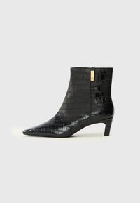 Bottines noires en matériau synthétique brillant avec une texture crocodile, bout pointu et petit talon. Accent doré à l'arrière.