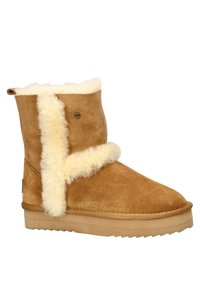 Tan suède enkellaars met een fluffy crèmekleurige bontvoering en een shearling accent. Rond neus en platte rubberen zool met een profiel voor grip.