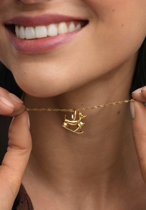 Collar de oro con un colgante de perro mecedor; la cadena es retorcida para dar textura. El colgante tiene un diseño detallado y caprichoso.