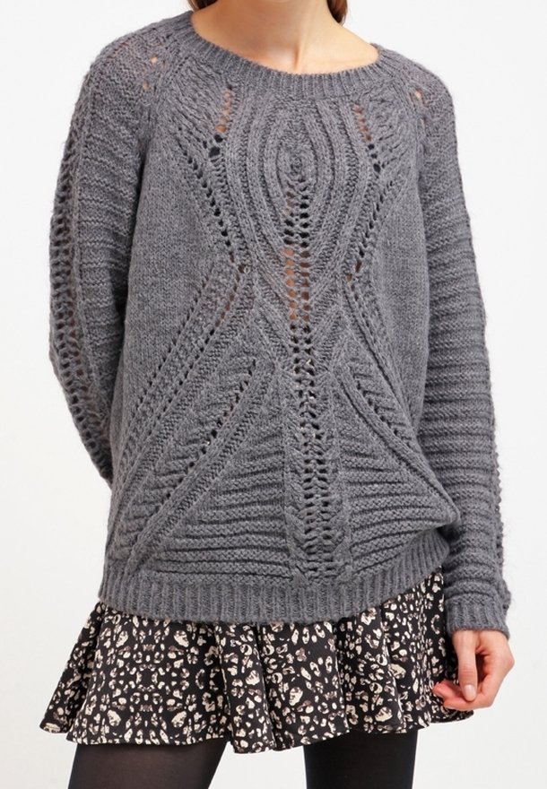 Gray knit sweater with a textured design and large stitches, featuring openwork patterns. Paired with a black skirt with a floral print.