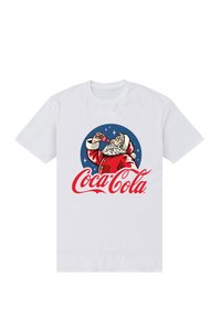 Hvid bomulds T-shirt med et motiv af julesmanden, der holder en Coca-Cola flaske, omridset i rødt mod en blå cirkulær baggrund.