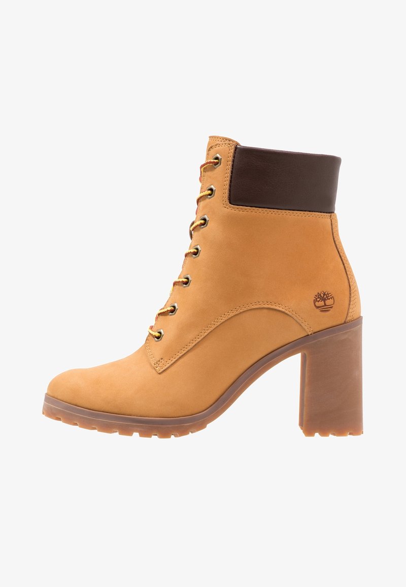 Bottine en cuir fauve avec talon bloc, laçage à l'avant, col rembourré marron foncé et petit logo embossé sur le côté.