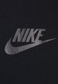 Tela negra con un acabado mate que presenta un gran logo y diseño de swoosh en gris de Nike. El material parece texturizado con costuras visibles.