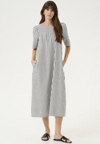 Juostuota juodai balta suknelė iki kelių, su trumpomis pūkuotomis rankovėmis, šoninėmis kišenėmis ir laisvu siluetu. Lengvos audinio tekstūros.