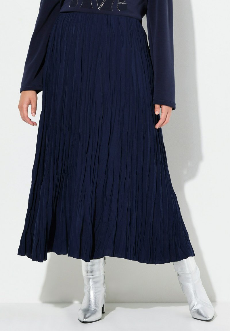 Gonna plissettata blu navy con un design tessurizzato, che arriva fino a metà polpaccio, abbinata a stivali metallici argento al ginocchio.