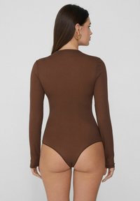 Hnědý proužkovaný body s dlouhým rukávem a vysokým vykrojením na nohách, přiléhavý střih, hladká textura a minimální švy.