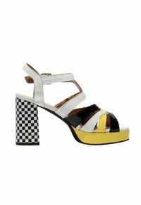 Sandale à talon haut avec des brides blanches, noires et jaunes, une plateforme jaune et un talon carré à carreaux noirs et blancs.