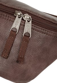 Hnědá taška z texturované kůže s dvojitým zipovým uzavíráním. Má stříbrné kovové detaily a pevné švy. Kompaktní, zakřivený tvar.