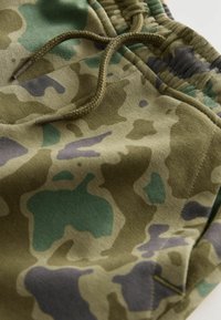 Camo-gepatroneerde stof in tinten groen, bruin en paars. Heeft een trekkoord in de taille en een zachte textuur.