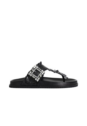Sandali flat neri in materiale sintetico testurizzato, caratterizzati da una larga fascia decorata con dettagli in strass e una chiusura a fibbia.