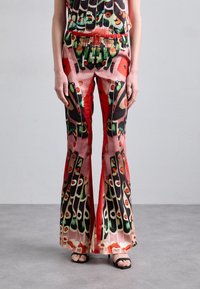 Pantalons évasés de couleur rouge vif, ornés de motifs complexes d'yeux et de formes abstraites. Fabriqués en tissu doux avec une taille élastique.