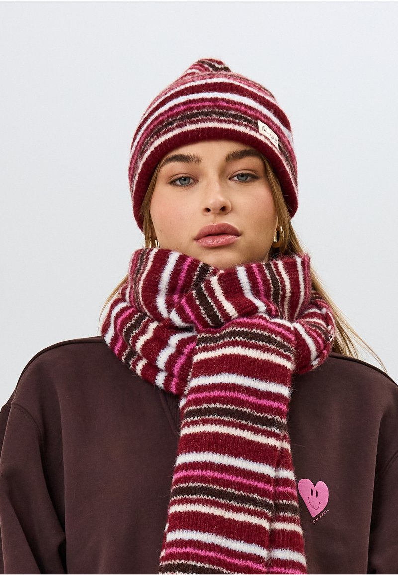 Set di berretto in maglia e sciarpa con strisce color maroon, rosa e bianco; texture morbida con un piccolo etichetta sul berretto e una lunga sciarpa drappeggiata.