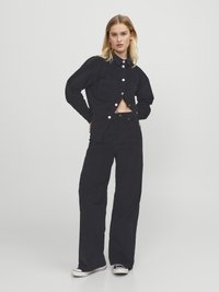 Black corduroy jacket with front pockets and button closure, paired with matching high-waisted pants. Both have a textured finish.