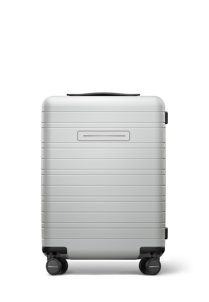 Silver hard-shell suitcase with horizontal ridges, black wheels, and a top handle. Sleek design, rectangular shape, minimalist features.