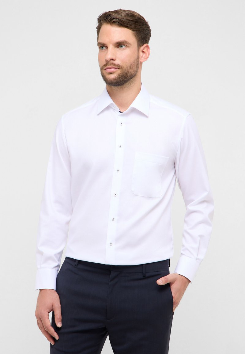 Wit overhemd met lange mouwen, een puntige kraag, een borstzak en contrasterende metalen knopen. Gladde stof met een aansluitend silhouet.