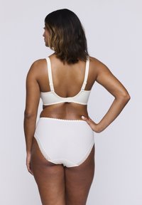 Krämfärgad bh och höga trosor med vågiga kanter, utrustade med justerbara remmar och en mjuk, slät textur.