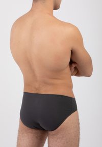 Costumi da bagno grigi scuri realizzati in tessuto liscio, vestibilità aderente con un design a vita bassa, cuciture minime e senza pattern o dettagli visibili.