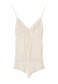 Kremowa koszulka na ramiączkach z koronkowym wykończeniem, z regulowanymi ramiączkami, posiadająca warstwowy krój oraz detal z wiązaniem z przodu.