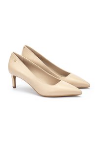 Zapatos de charol beige con punta afilada y tacón bajo. Textura suave con un sutil acento de logo en el costado. Diseño elegante adecuado para diversas ocasiones.