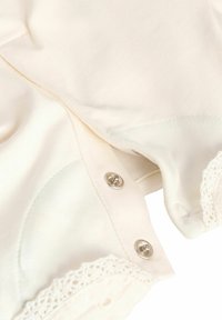Cremfarbendes Kleidungsstück mit Druckknöpfen und Spitzenbesatz. Verfügt über einen weichen Stoff mit glatter Textur und runder Halslinie.
