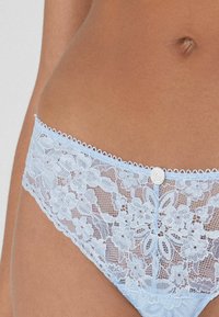 Light blue lace panties featuring floral patterns, scalloped edges, and a decorative white button at the front center. Soft and delicate texture.