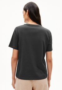 Graues Baumwoll-T-Shirt, kurze Ärmel, lockere Passform, runder Ausschnitt, glatte Textur, genähter Saum, getragen mit hellen, lockeren Hosen.