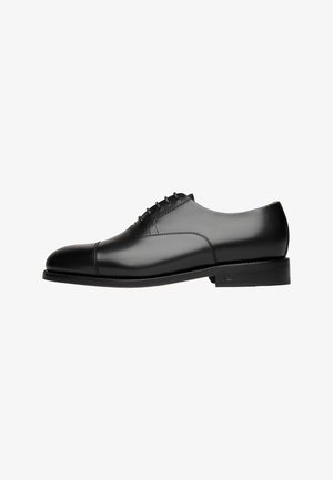 Chaussure oxford en cuir noir avec un bout arrondi, des détails de couture subtils, un laçage et un talon plat noir. Texture lisse sur l'ensemble.