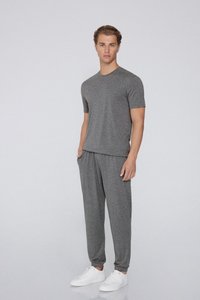 Graues Kurzarm-T-Shirt und passende tapered Hose aus einem weichen, strukturierten Stoff, kombiniert mit weißen Sneakern.
