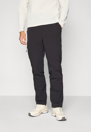Black cargo pants made of durable fabric, featuring side pockets, a zippered pocket, and a straight leg design. Worn with light sneakers.